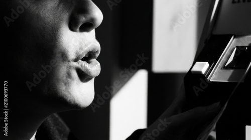 Close Up Of A Person Blowing A Kiss While Holding A Photo Slide In Black And White