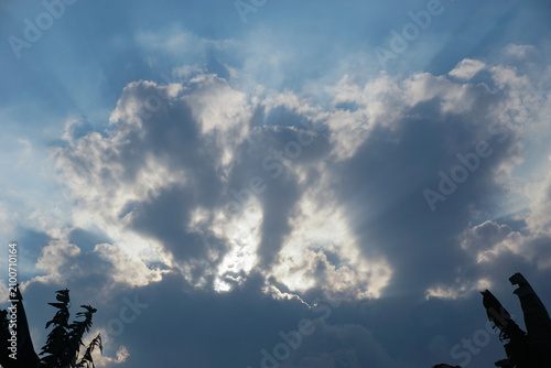 Obraz na plátně Sunlight and dusk light penetrate the dark cloud formations in the blue sky, a powerful, hopeful, and majestic natural phenomenon