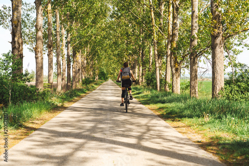 Female cyclist riding along country road during summer bicycle tour