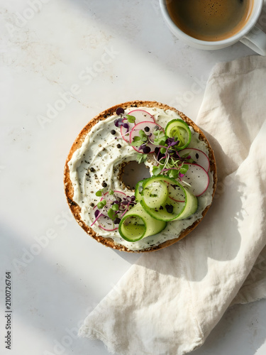 Vegan bagel with cucumber and radish on light stone background