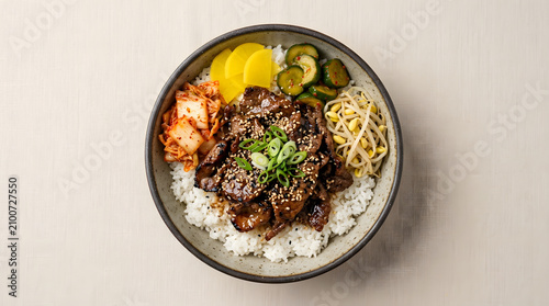 A bowl of steamed rice topped with juicy Korean BBQ beef, sesame seeds, sliced green onions, kimchi, and pickled vegetables.