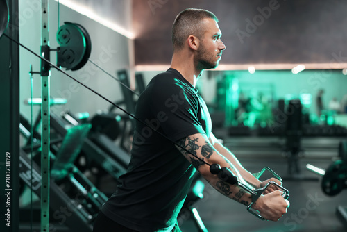 Foto Strong man training on cable crossover machine in gym
