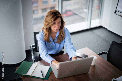Принти на полотні Confident middle-aged businesswoman using her laptop in a modern office