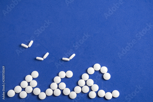 Obraz na płótnie White pills arranged as ocean waves, seagulls flying, creative seaside medication concept