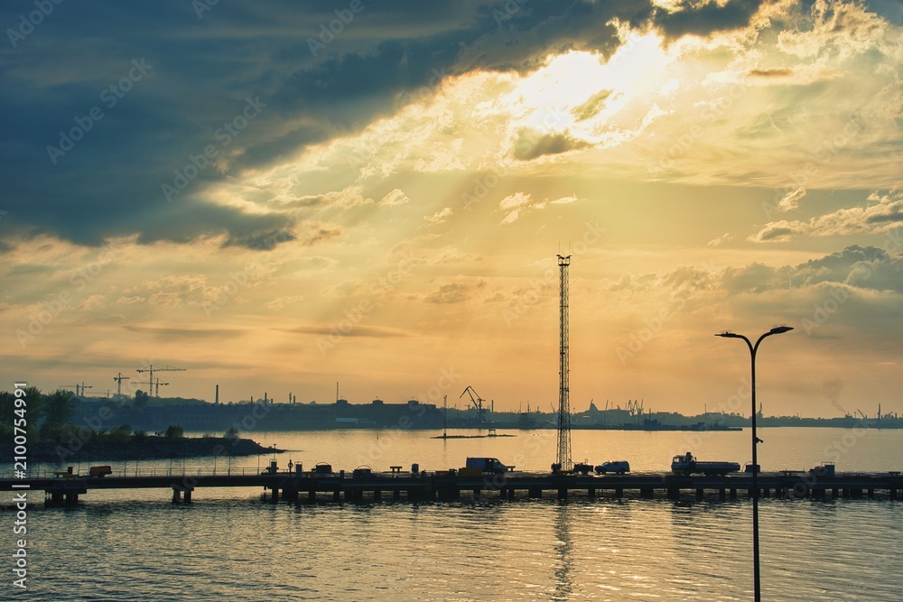 Fototapeta premium Dramatic Sunset and Sun Rays over Tallinn Port Pier Silhouette