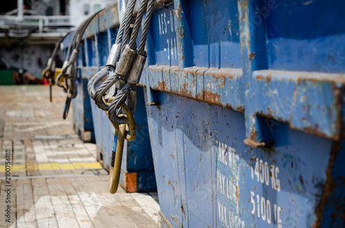 Cargo skips secured on the main cargo deck of an offshore support vessel. The cargo skips are fitted with lifting slings and shackles for safe handling by offshore cranes during the transportation