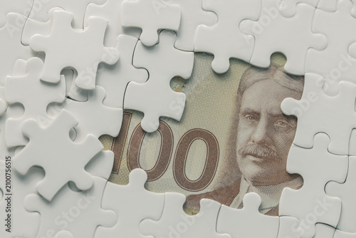 Canada money. 100 Canadian dollar banknote among scattered puzzle pieces. Business concept. Financial analysis. CAD currency exchange rate. Interest rates. Copy space. Business background.