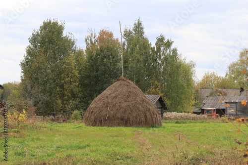 Tableau sur toile A haystack near old houses on an autumn day