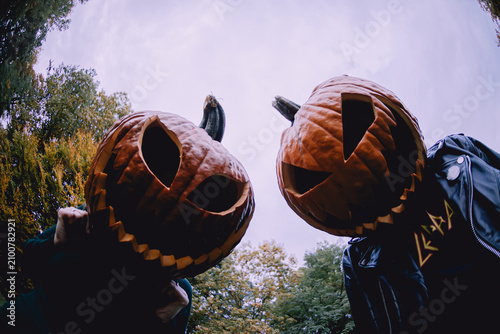 Foto Couple, looking like maniacs, with jack-o'-lantern pumpkins on their heads looking down at a camera