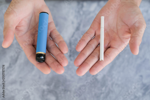 Fotografía A man is holding a cigarette and a vape (electronic cigarette)