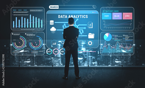 Принти на полотні Professional Man Analyzing Data Analytics Dashboard Displayed on Transparent Screen with Cityscape Background at Night Fluxor