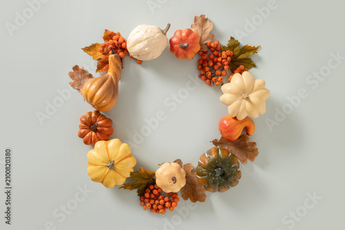 Autumn pumpkin wreath with berries and leaves on blue background