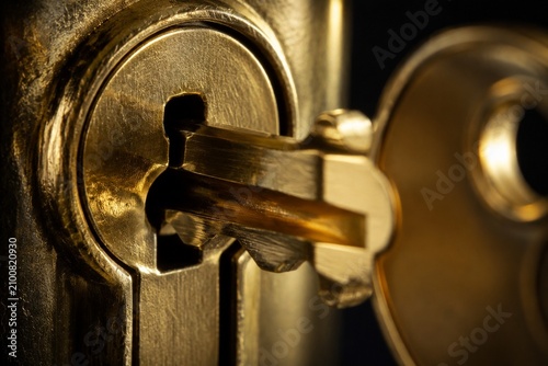 A brass key turning in a classic lock's keyhole, metallic glint.