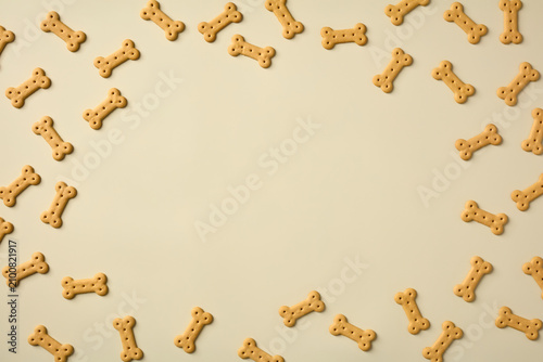 Bone-shaped dog biscuits forming a border frame on a light beige background with copy space in the center.