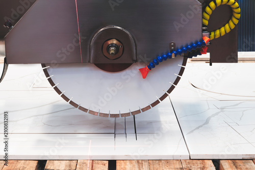 circular saw cuts a marble stone slab with a sharp blade. The rotating blade precisely cuts the tile. Stone industry, tech industrial technology background