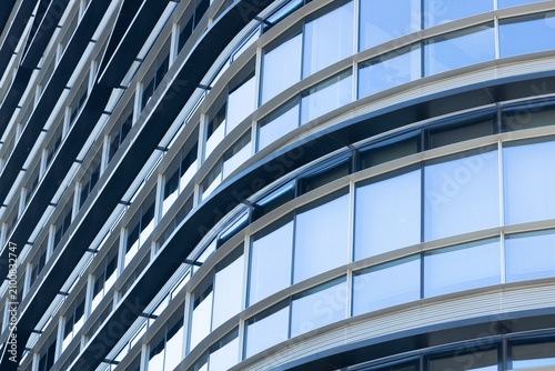 Modern architectural building facade featuring curved glass windows and metallic frames, showcasing contemporary design elements in an urban environment