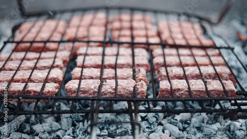 Minced meat rolls sizzling on a barbecue over hot charcoal