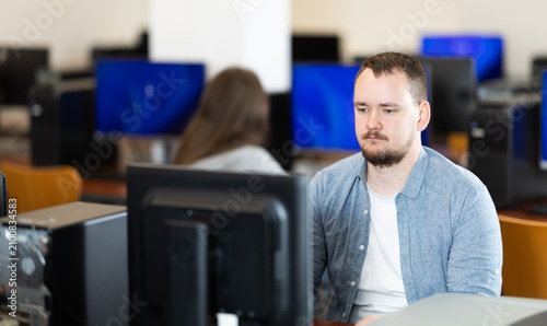 Foto Guy student of computer courses types on keyboard, performs work, educational practical task
