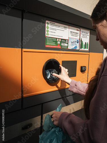 Krotoszyn, poland - 20 06 2026: Young woman inserting plastic water bottle into reverse vending machine, eco recycling concept
