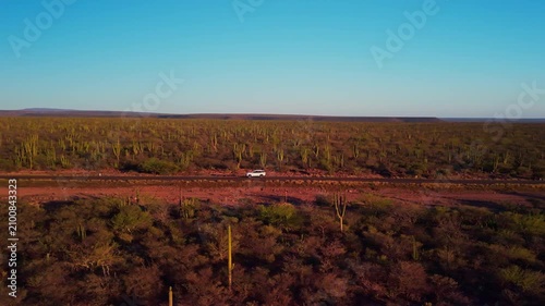 Car driving through desertic landscape at sunset