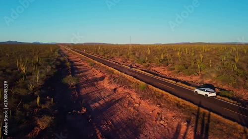 Car driving through desertic landscape at sunset