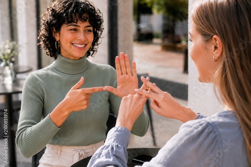 Women communicating in sign language in front of a street cafe