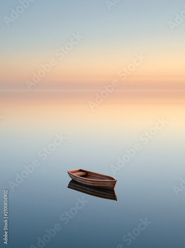 A small wooden boat floats peacefully on perfectly still water reflecting a pastel gradient sky at dawn, creating a serene and minimalist scene.