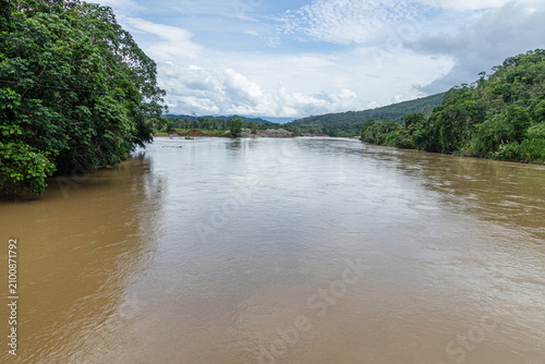 A river landscape at the Port of Chuchumbletza of the Zamora river, surrounded by dense tropical rainforest vegetation in the Amazon region of Ecuador
