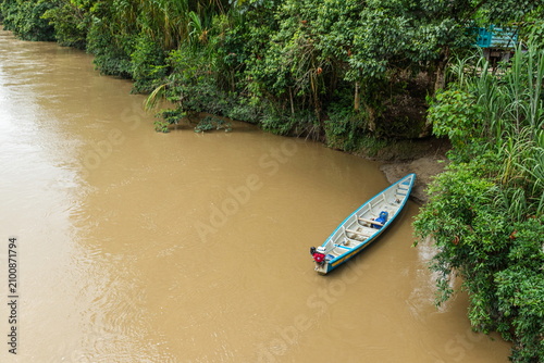 An aerial view of a traditional wooden boat or canoe docked at the port of Chuchumbetza on the Zamora River, an important river transportation hub and a tourist destination in Ecuador's Amazon region