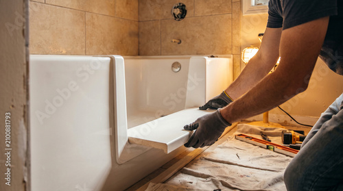 Plumber installing accessible walk in bathtub at home