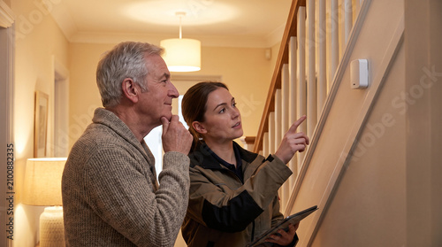 Female technician showing smart safety sensor to senior