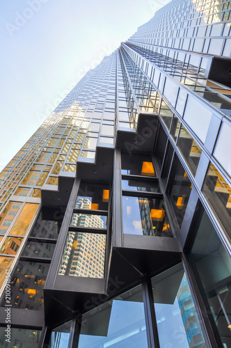 Looking up at a modern glass residential high-rise building against a blue sky in downtown Toronto, Ontario, Canada.