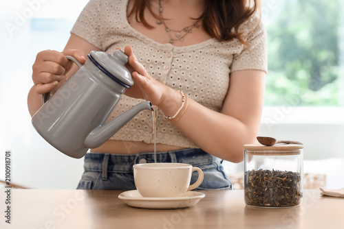 Woman pouring hot tea from ...