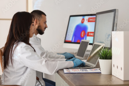 Young doctors with laptops analyzing scientific data at desk in laboratory