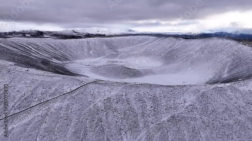 Aerial view of Hverfjall volcano revealing its giant snowy crater - Horizontal forwards drone video