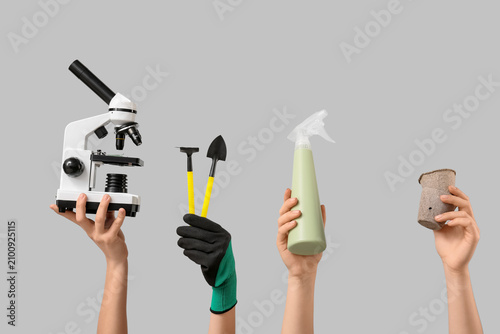 Female hands with modern microscope, gardening tools, water sprayer and peat ...