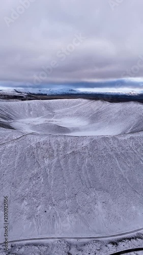 Vertical drone shot revealing a giant circular volcanic crater in winter in Northern Iceland - Aerial forwards shot