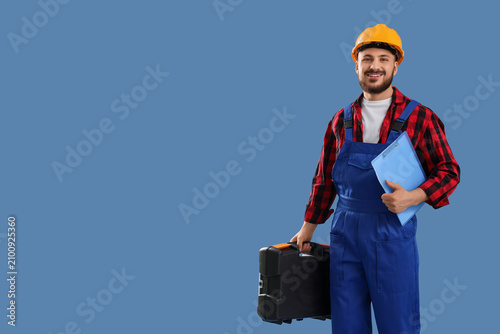 Male constructor with clipboard and tool kit on blue background