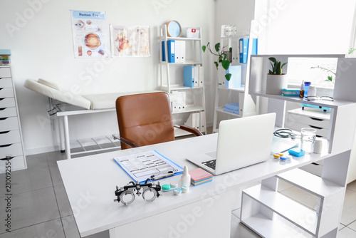 Interior of oculists cabinet with shelving units, trial frame and laptop on w...