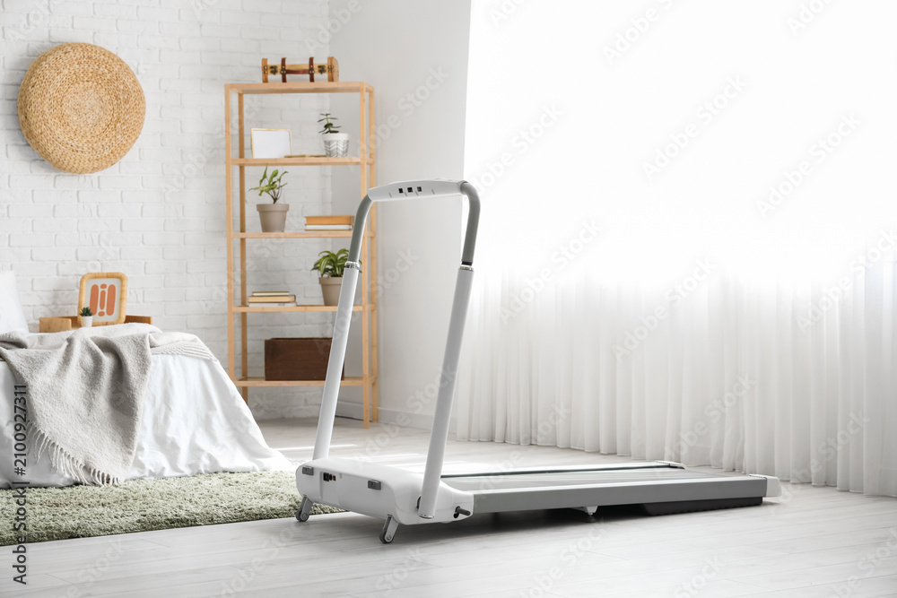 Obraz premium Interior of light bedroom with treadmill and shelf unit