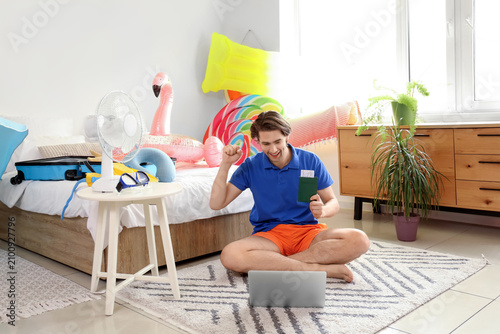 Male tourist with passport video chatting in bedroom on vacation