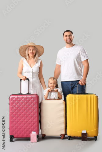 Happy family with suitcases on grey background