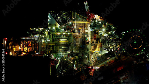 Cuadro en lienzo Oil Drilling Rig Dominates Dark Industrial Landscape at Night, showcasing coloss