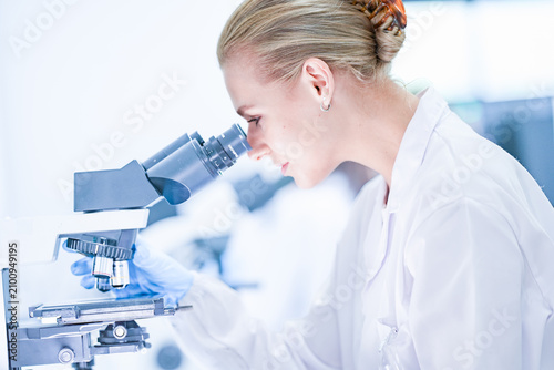 Фотография Medical pathologist looking through microscope eyepiece for cancer diagnosis