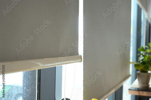 bright and minimalist interior scene featuring roller blinds covering large window