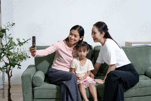 Foto Two women and a young girl sit on a sofa at home while taking a sulfide with a s