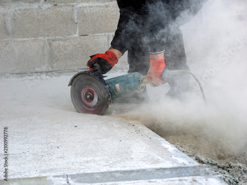 bricklayer processing concrete slabs with a disc grinder