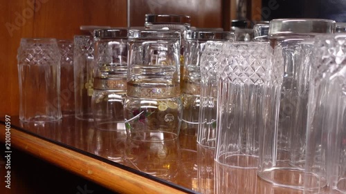 Clear glass cups on a wooden shelf in a kitchen