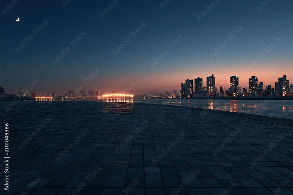 Fototapeta premium City skyline at dusk with illuminated structures reflected on water