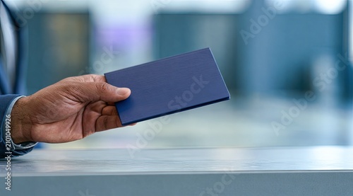 Hand holds a dark blue passport over a counter